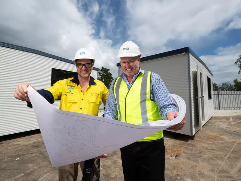 workers smiling outside whole looking at plans
