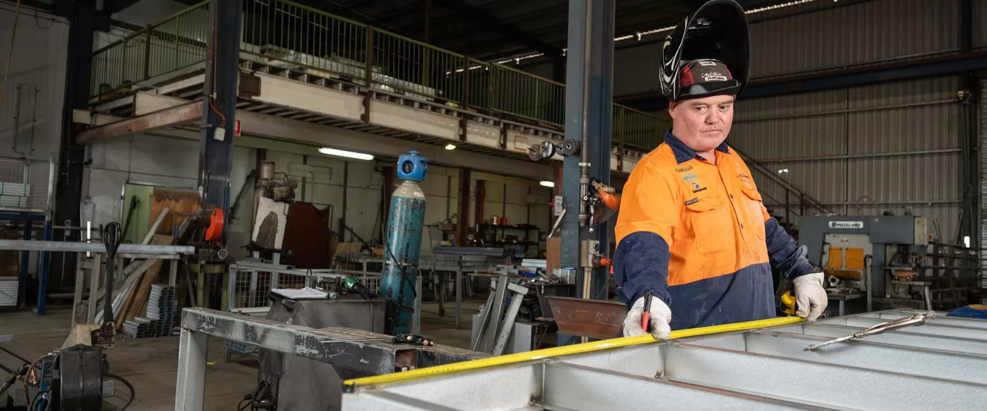 man with welding mask using tape measure